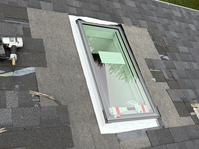 Skylight installation in progress on a shingle roof